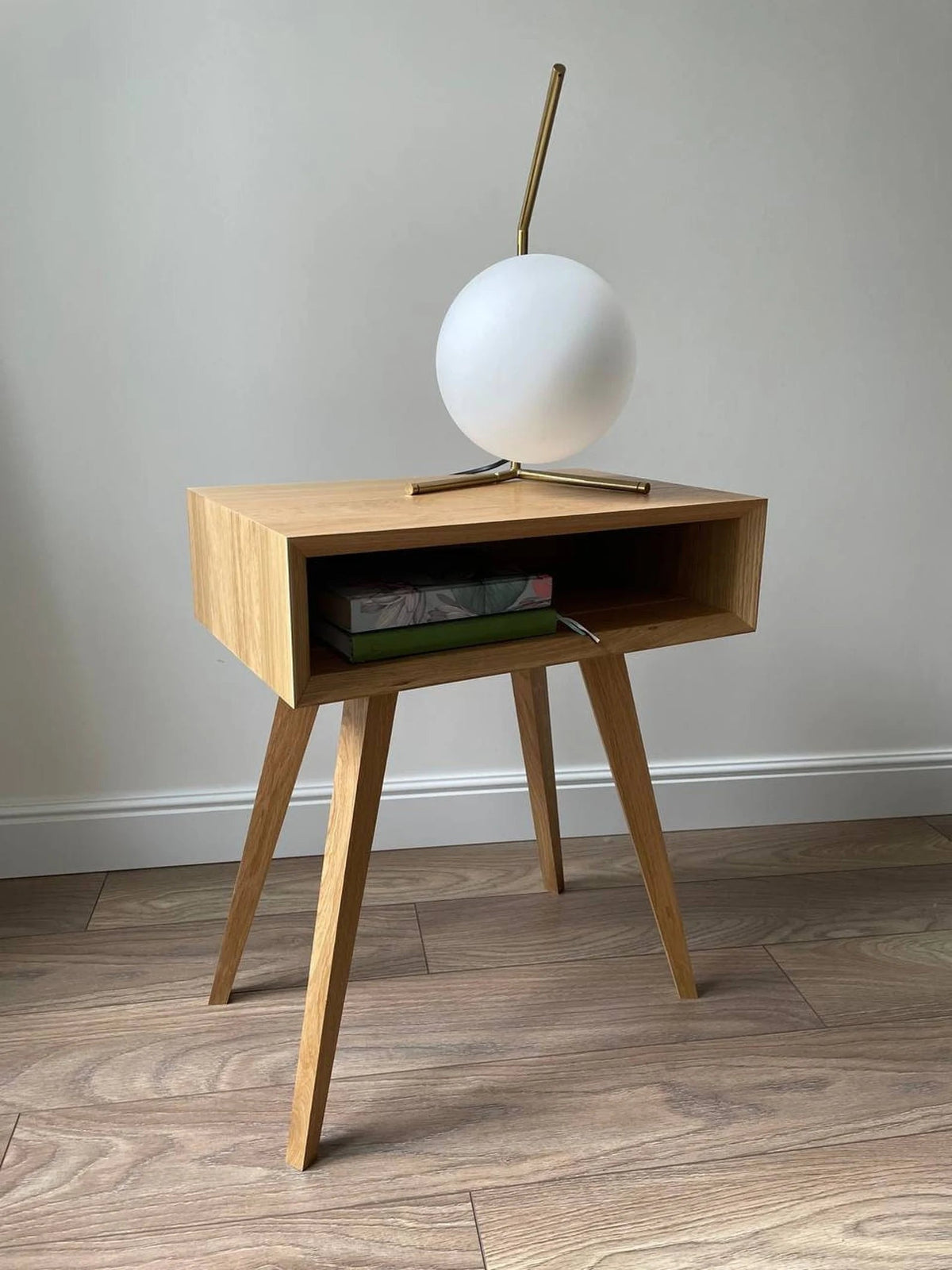 Oak side table with open compartment and globe lamp on top