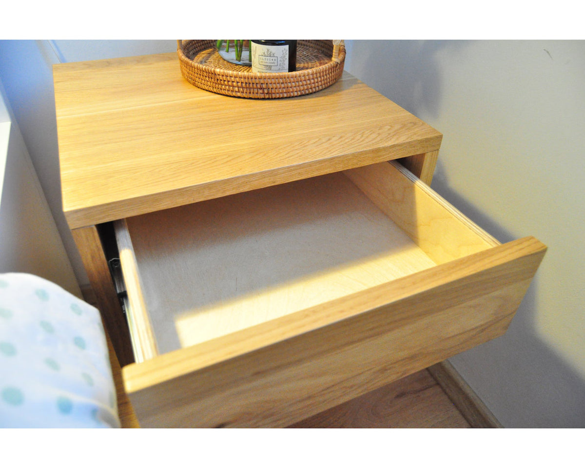 Close-up of oak nightstand drawer fully open showing smooth wood interior